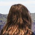 a woman standing on a ledge overlooking a valley