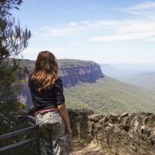 a woman standing on a ledge overlooking a valley