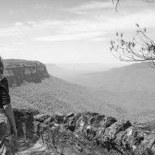 a woman standing on a ledge overlooking a valley